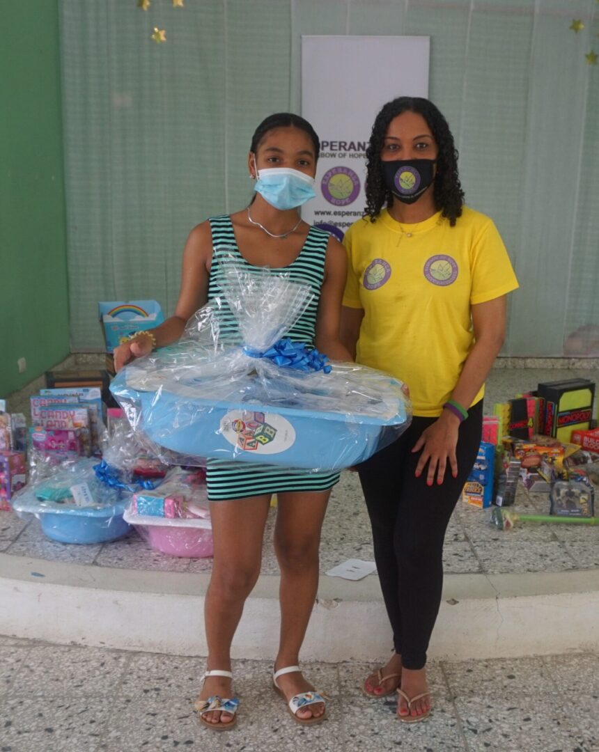 Our staff and a girl holding a blue basket of baby supplies