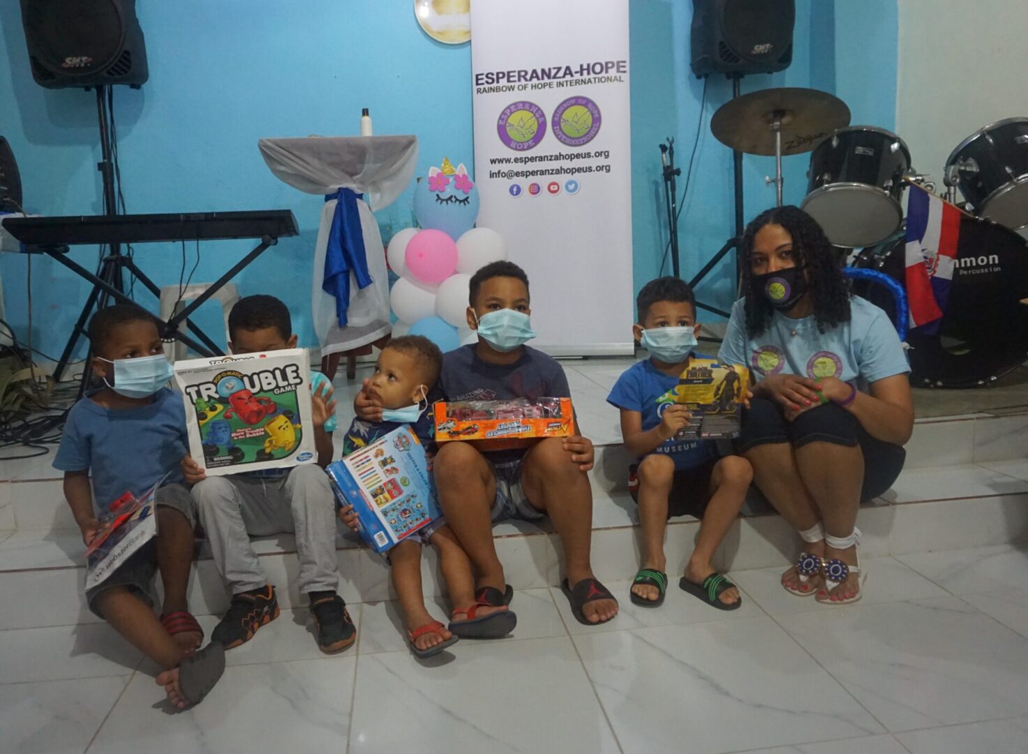 Our staff and five boys sitting near the drum set, holding their toys