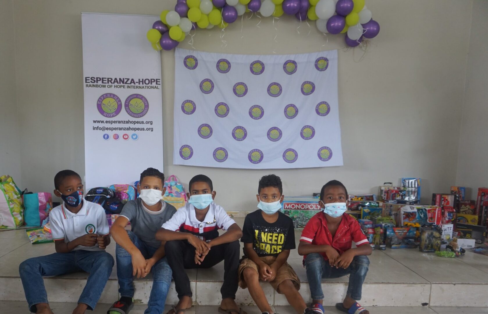 Five boys wearing masks sitting on the elevated area with many toys