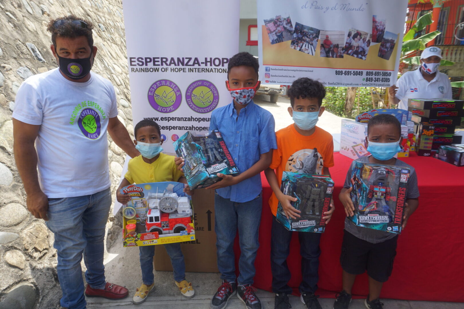 A male staff and four boys each holding a box of toys