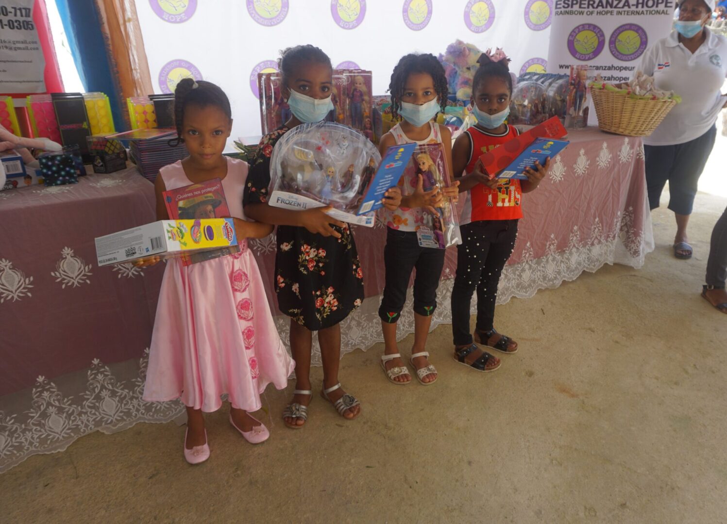 Four young girls wearing masks and holding books and toys, batch 5