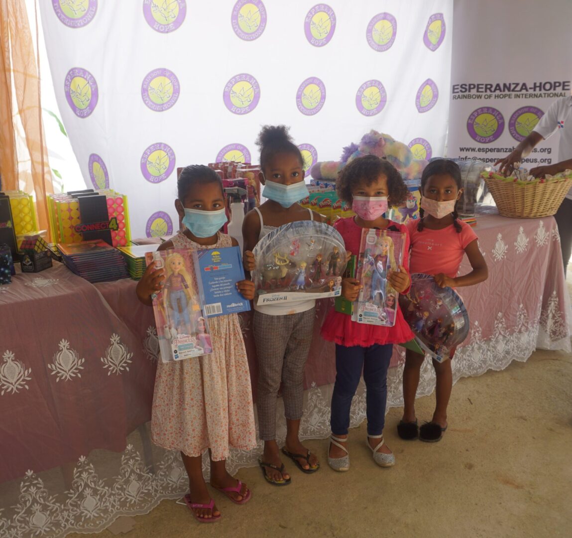 Four young girls wearing masks and holding books and toys, batch 3
