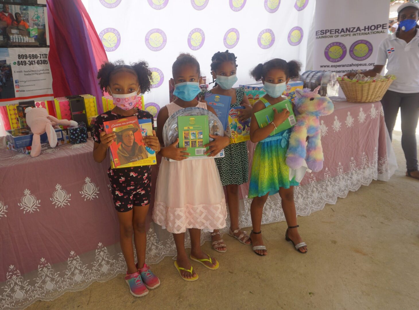 Four young girls wearing masks and holding books and toys, batch 6