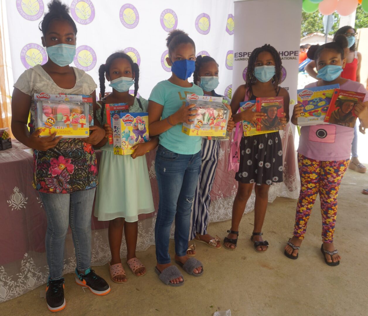 Six girls holding toys, the cloth with Esperanza-Hope logo behind them, batch 2