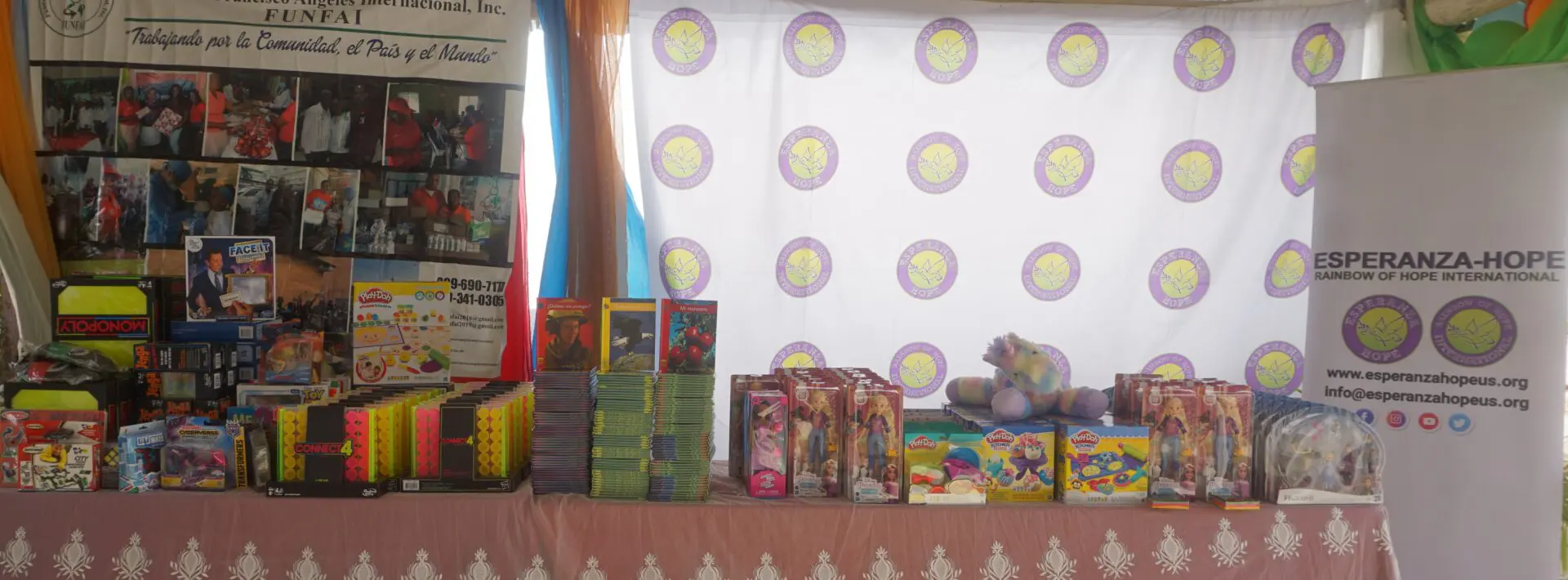 A table full of books and toys and a cloth with Esperanza-logo behind it