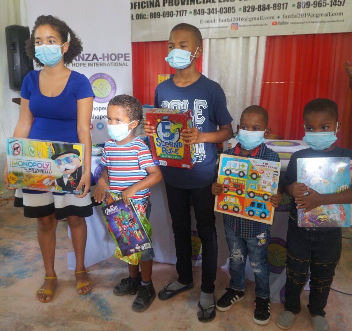 A girl and four boys wearing masks, each holding a boxed toy
