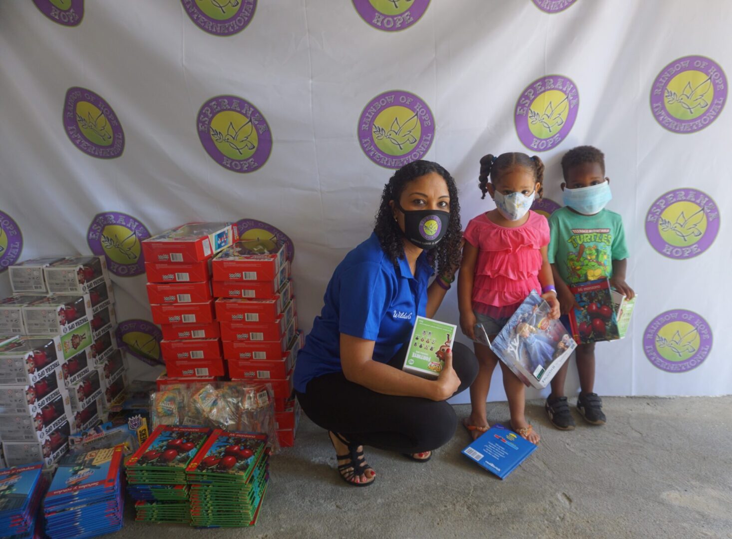 Our staff and two young kids holding their toys and books
