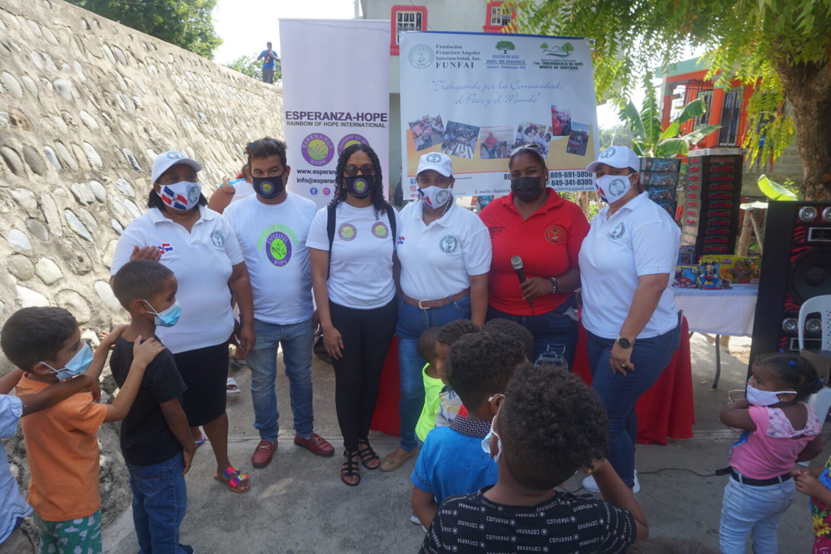 Six of our staff wearing masks, standing in front of the children in line (version 2)