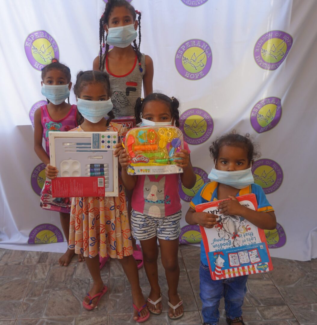 Five girls standing against the Esperanza-Hope backdrop with their toys and books