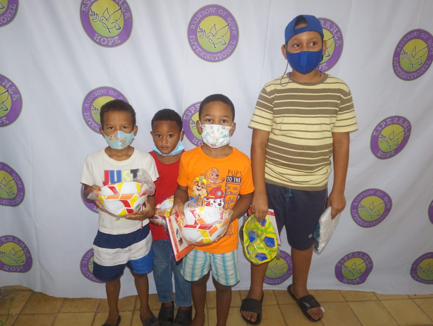 Four boys holding toys against the Esperanza-Hope backdrop, batch 2