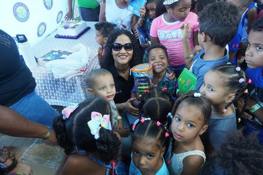 Woman surrounded by joyful children at a community event.